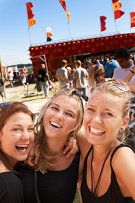 Buy stock photo Three young girls standing together and smiling at a music festival