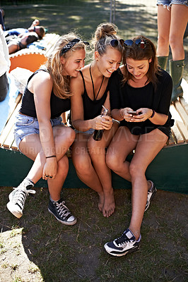 Buy stock photo Three friends sitting together and sharing gossip at a music festival