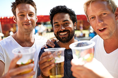 Buy stock photo Three young men toasting their beers at a music festival