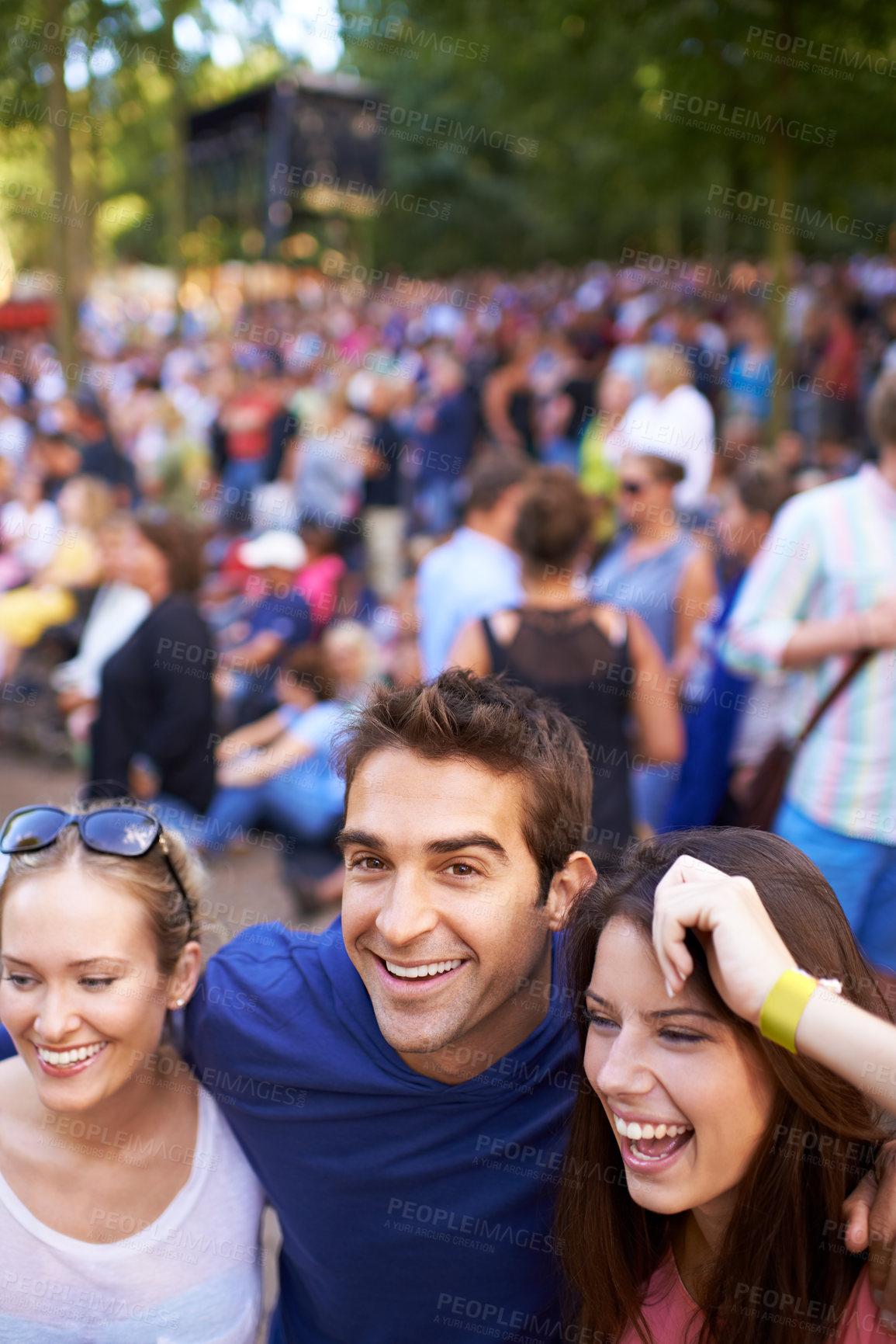 Buy stock photo A group of smiling friends enjoying a music festival with crowd in the background