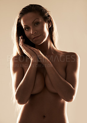 Buy stock photo Shot of a gorgeous young woman covering her breasts against a gray background
