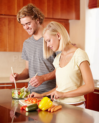 Buy stock photo A young couple preparing some food in the kitchen