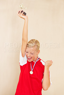 Buy stock photo Woman, soccer player and trophy or a winner celebrate on a plain background for football achievement. A young female sports person or athlete with fist and champion medal award for winning a game