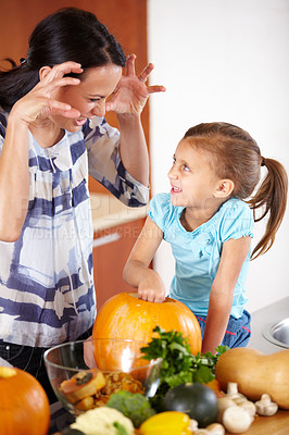 Buy stock photo Playful, pumpkin for halloween and a mother with her daughter in the kitchen of their home together for holiday celebration. Smile, happy or funny face with a woman and girl child carving a vegetable