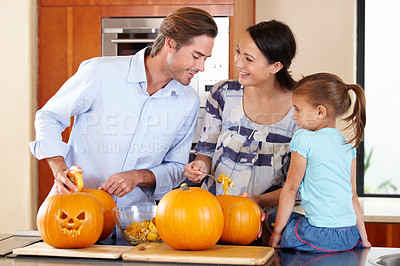 Buy stock photo A young mother and father standing with their young daughter in a kitchen preparing Jack O'lanterns for Halloween