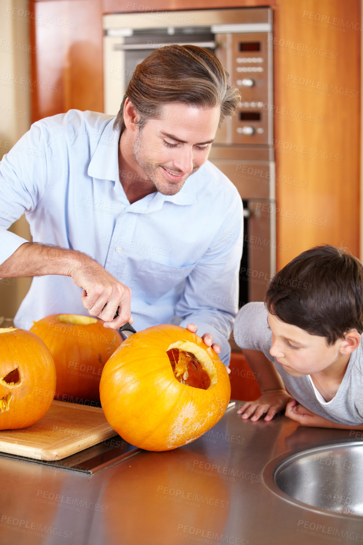 Buy stock photo Halloween, pumpkin and father with kid in a kitchen for carving, learning or festival preparation at home. Family, love and parent with fruit, knife and creative lesson while. bonding with boy child