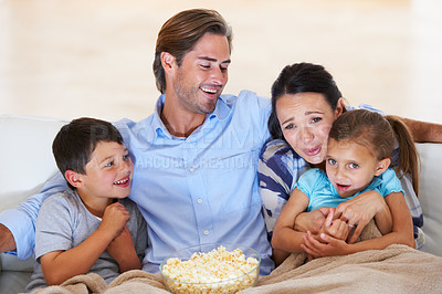 Buy stock photo Cute young family watching a movie together at home on the couch