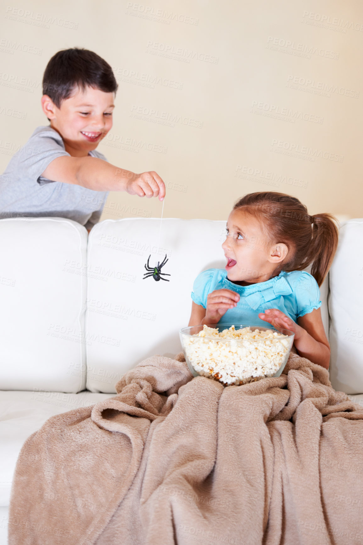 Buy stock photo Mischievous young boy scaring his little sister at Halloween with a rubber spider