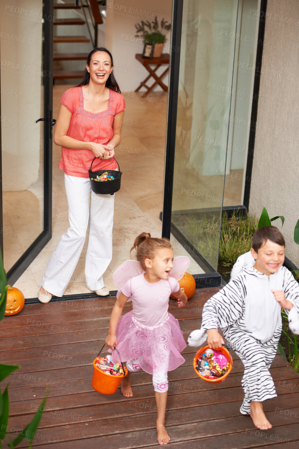 Buy stock photo Family home, halloween and children running with candy for fun, adventure or vacation tradition. Happy, love and mother watching excited kids in costume, laugh and playful energy for holiday prank