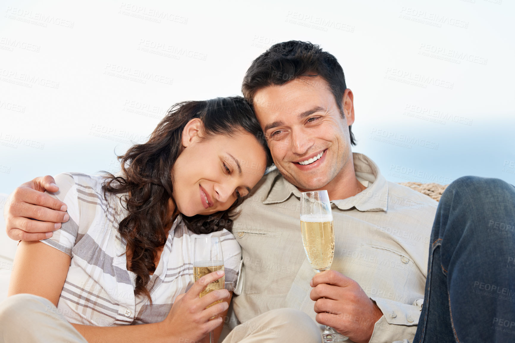 Buy stock photo A cute couple drinking champagne with the ocean in the background