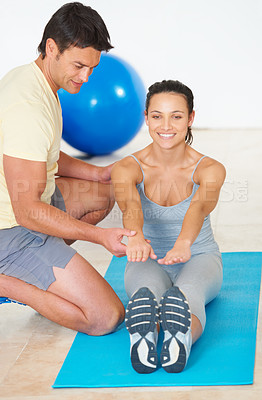 Buy stock photo A fitness instructor showing a young woman how to do an exercise