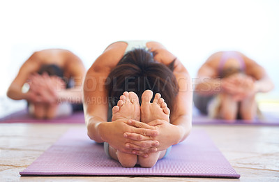 Buy stock photo Young yoga instructor leading a class in stretching