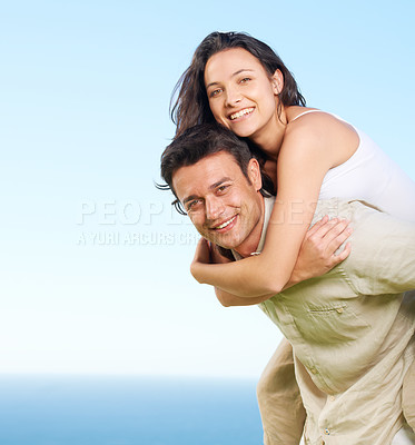 Buy stock photo A young man piggybacking his girlfriend with a view of the ocean in the background