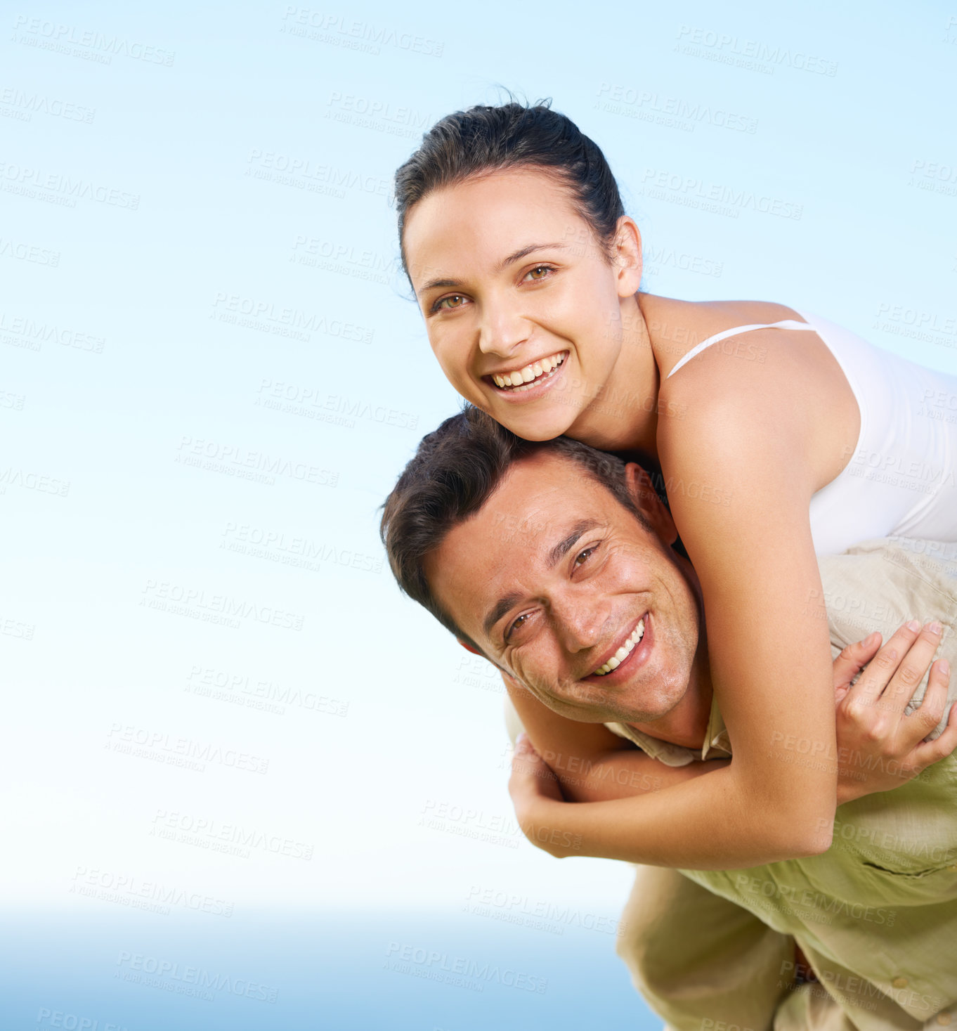 Buy stock photo A young man giving his girlfriend a piggyback with the ocean in the background
