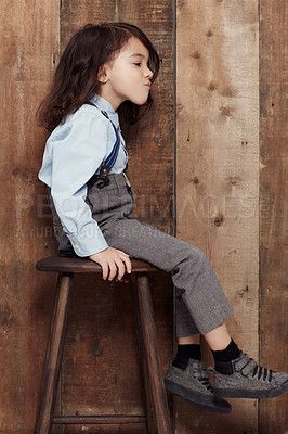 Buy stock photo Shot of a cute little boy in old-fashioned overalls sitting on a stool