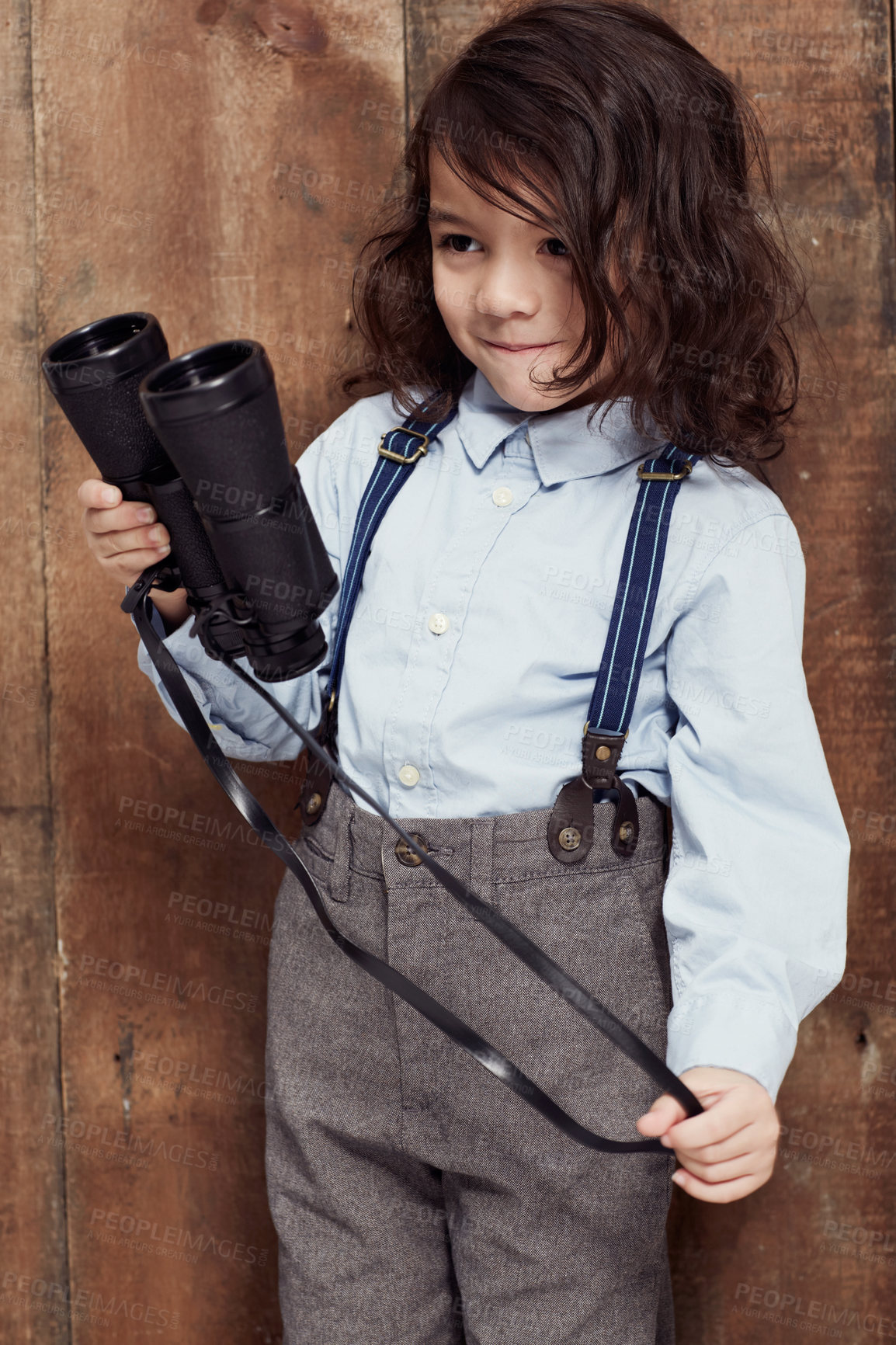 Buy stock photo Vintage, child and boy with binoculars or fashion, style and clothes for costume on wood background or studio. Retro, kid and confidence in old fashioned spy aesthetic with shirt and suspenders