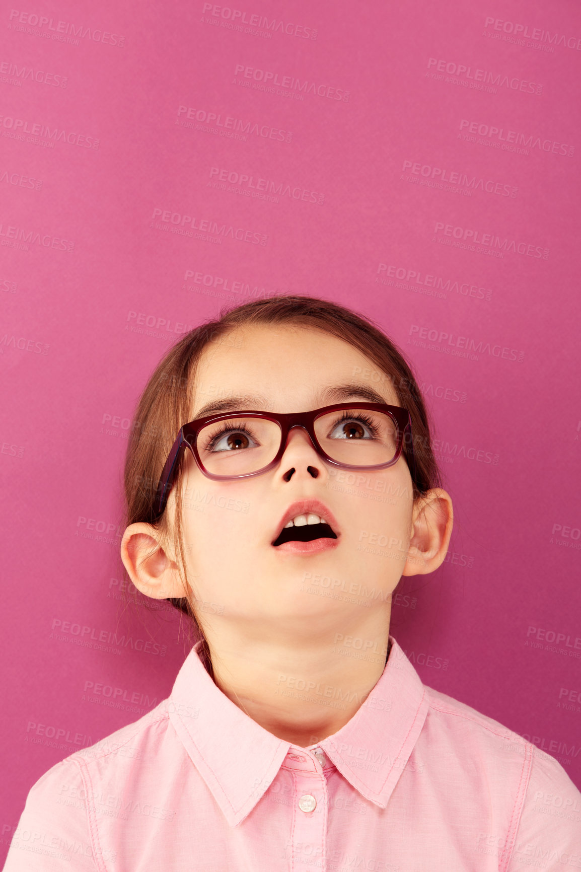 Buy stock photo A little girl wearing spectacles looking up against a pink background
