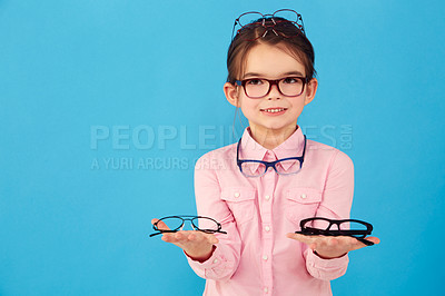 Buy stock photo Portrait, mockup and choice by kid with glasses for vision or eye care promotion isolated in a blue studio background. Smile, decision and girl child with sale, discount and deal option for eyewear