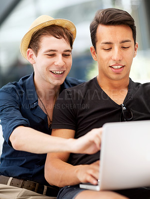 Buy stock photo Shot of a young man pointing at his friend's laptop