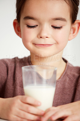 Buy stock photo Cropped shot of a cute little girl looking happily at a glass of milk