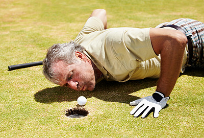 Buy stock photo Golf, man and blowing ball into hole on a grass field for player match and putting. Fitness, sport and funny mature male person playing on a lawn to blow golfer object into target space and cheating