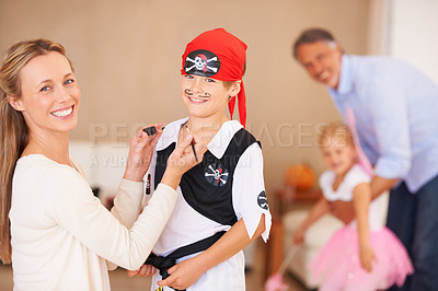 Buy stock photo Portrait of a mother painting a mustache on her sons face on halloween with father and sister playing in the background