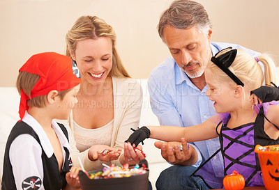 Buy stock photo A family sitting together and sharing sweets on halloween with children in fancy dress