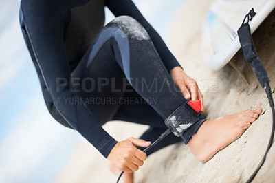 Buy stock photo Cropped shot of an unrecognizable female surfer attaching her surfboard to her ankle