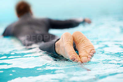 Buy stock photo Rearview shot of a man surfing in clear blue water