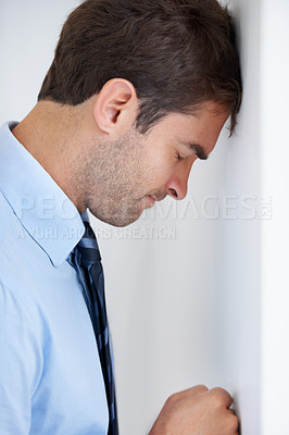 Buy stock photo Profile of a businessman standing with his forehead against the wall and his fist punching the wall