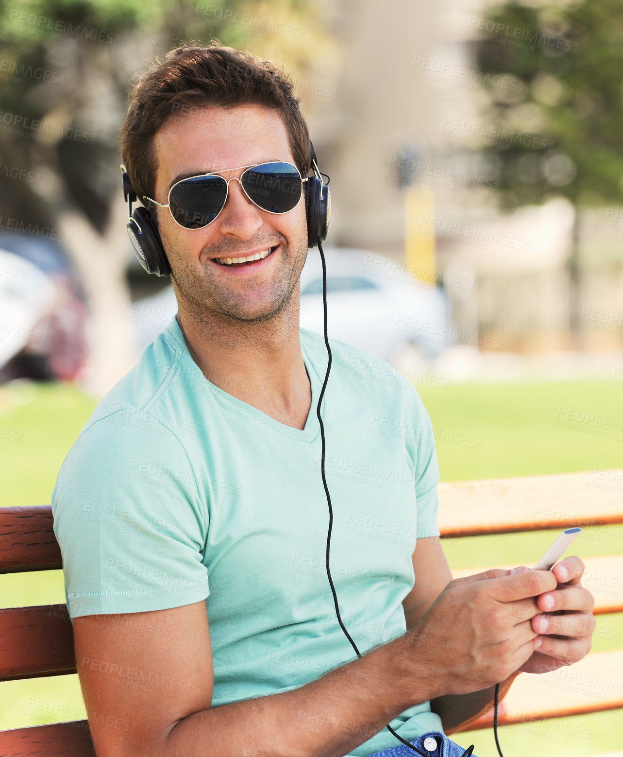 Buy stock photo Cellphone, happy and man with headphones in park for listening to music, audio and radio. Fashion, sunglasses and person for streaming subscription, song and playlist on holiday, vacation and relax