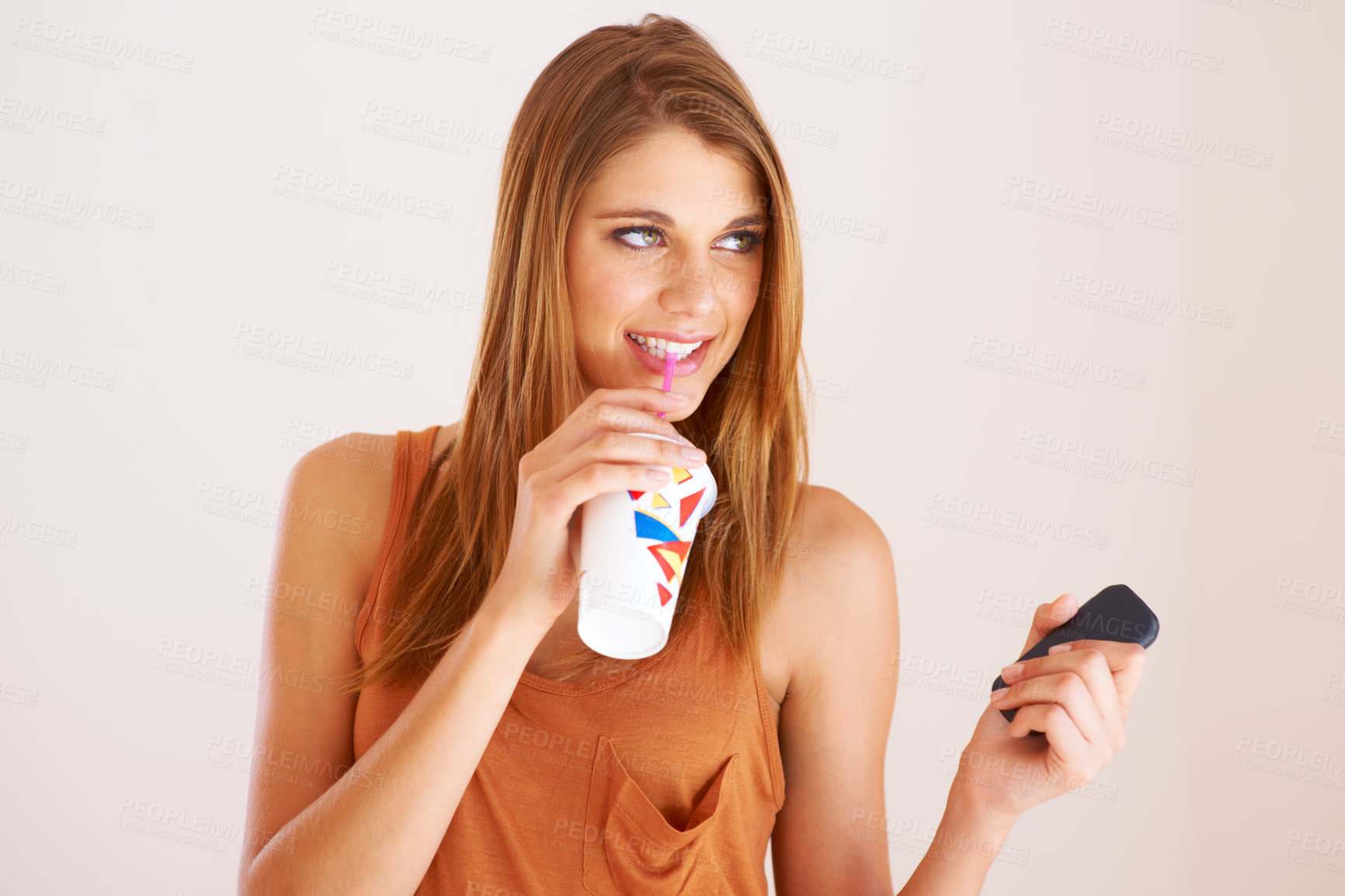 Buy stock photo Thinking, phone and a woman with drink in a cup in studio for retro style, vintage and takeaway soda. Casual female model person with a device on a white background with a smile, idea and happy gen z