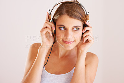 Buy stock photo A young woman listening to music on her headphones