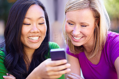 Buy stock photo Two young woman reading an sms together