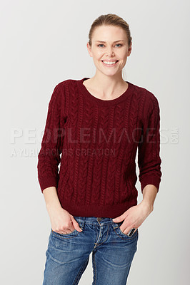 Buy stock photo Cropped studio portrait of a happy and attractive young woman standing with her hands in her pockets