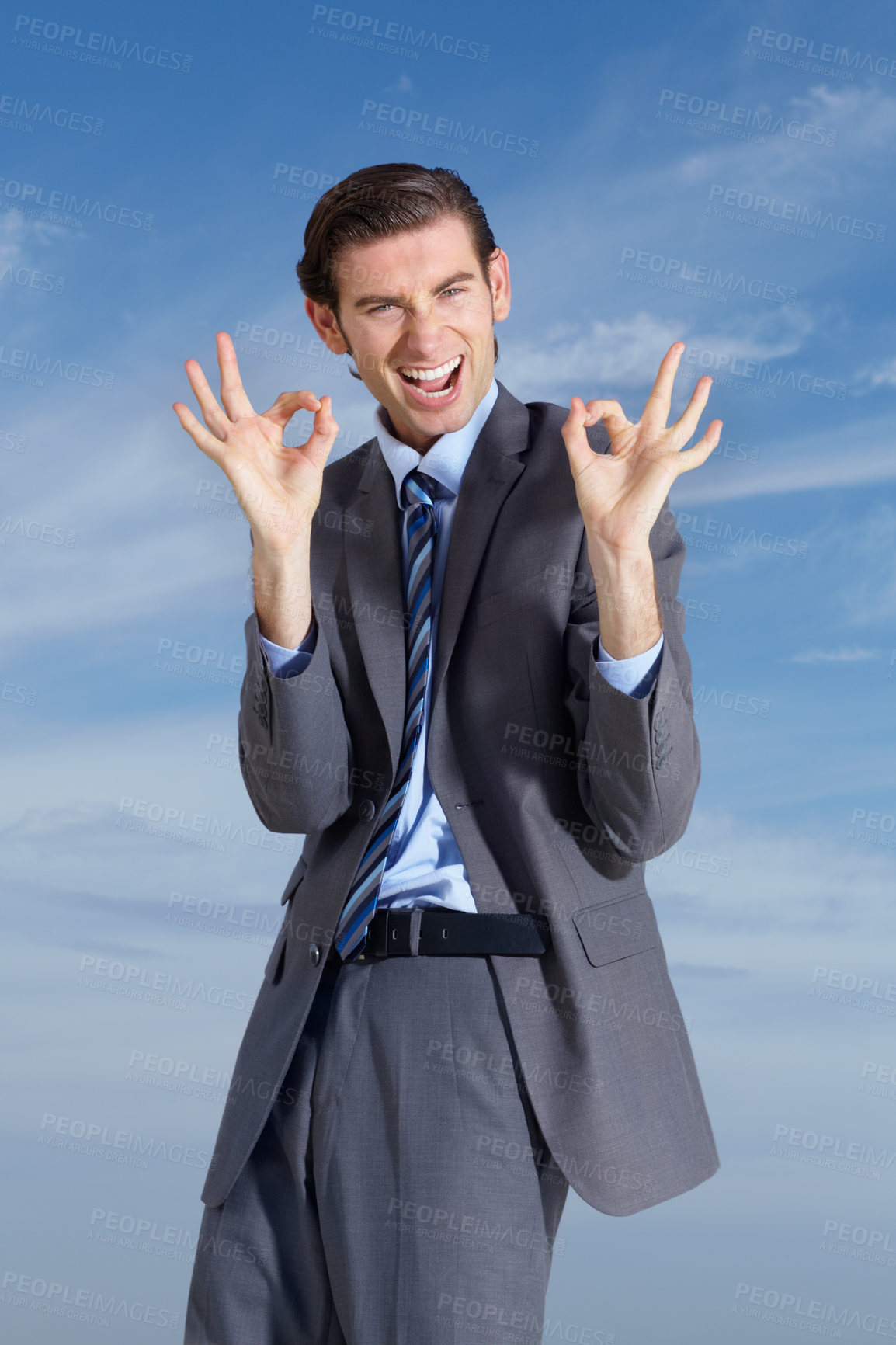 Buy stock photo A young businessman signing 'a-okay' against a blue sky