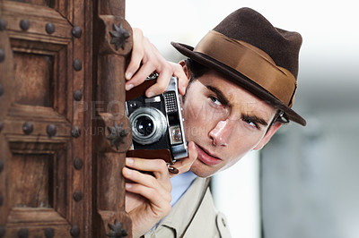 Buy stock photo Private detective capturing a photo suspiciously from around a corner while using a retro camera