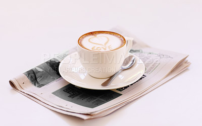 Buy stock photo Coffee cup, cappuccino and newspaper with heart in foam on a table with no people in a restaurant. Cafe drink, love writing and foamy beverage art with milk in a latte and a closeup of mug and spoon