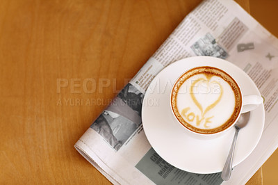 Buy stock photo Coffee, cappuccino and heart in foam with newspaper on a table with no people in a restaurant. Cafe drink, love writing and foamy beverage art with milk in a cafe with a closeup of mug and mockup