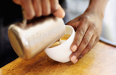 Buy stock photo Cropped shot of a barista pouring milk froth into a cappuccino