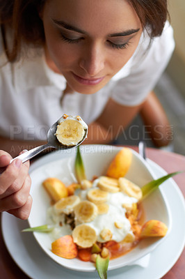 Buy stock photo Above, woman and eating fruits at restaurant for breakfast, healthy food and meal at diner. Young female person, spoon and bowl of fresh fruit salad for nutrition, wellness or detox at vegan cafe