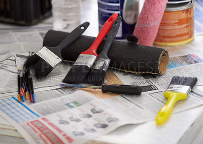 Buy stock photo Cropped closeup of paintbrushes and paint tins on newspaper