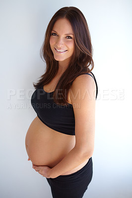 Buy stock photo Woman, pregnancy portrait and stomach by wall with smile, excited or pride for new life, future or family. Young mom, pregnant and holding belly with happiness, love or care in house with expectation