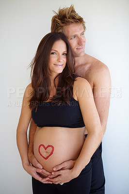 Buy stock photo Pregnant, hug and portrait of couple with heart on stomach for love, care and support on white background. Family, pregnancy and man and woman in studio excited for baby with love symbol on belly