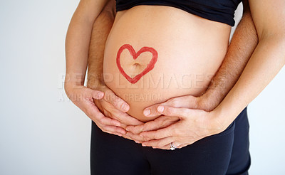 Buy stock photo Pregnant woman&#039;s belly with her partner&#039;s hands wrapped around her and a heart shape painted on it