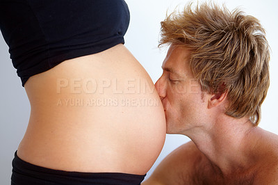Buy stock photo Man kissing stomach, pregnant woman and love, excited new parents in studio on white background. Marriage, support and pregnancy, mother and father with baby in belly and couple with future family.
