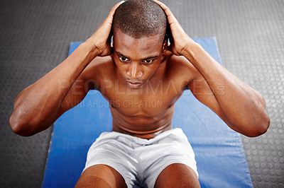 Buy stock photo Overhead shot of a focused man doing sit-ups on a mat in the gym.