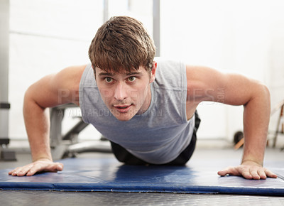 Buy stock photo Young man doing push ups on a mat in a gym