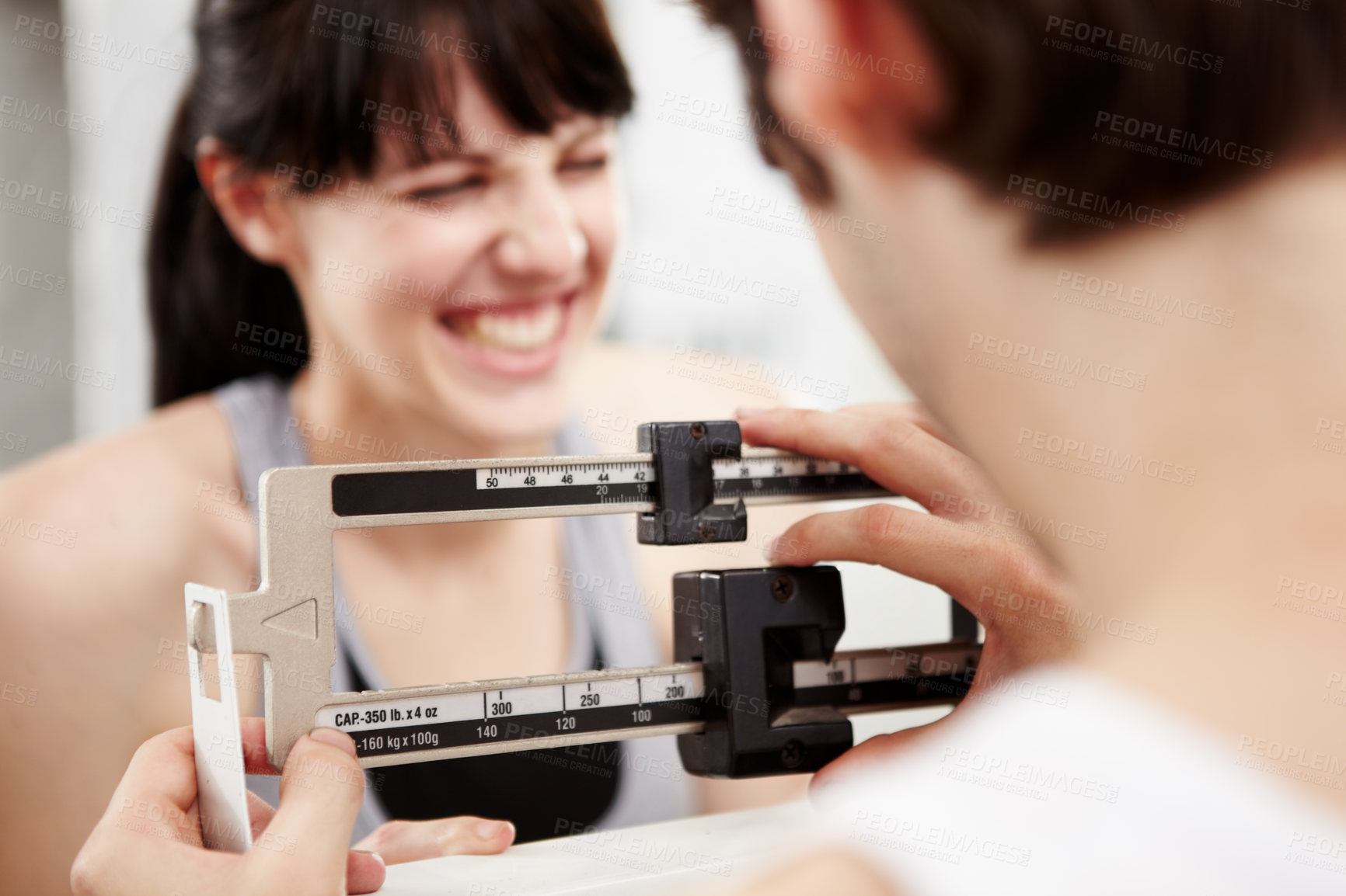 Buy stock photo Closeup cropped shot of a woman looking excited as her trainer measures her weight