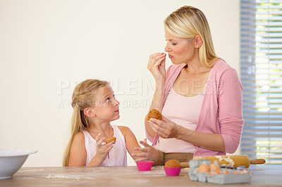 Buy stock photo A mother and daughter tasting the muffins they've baked